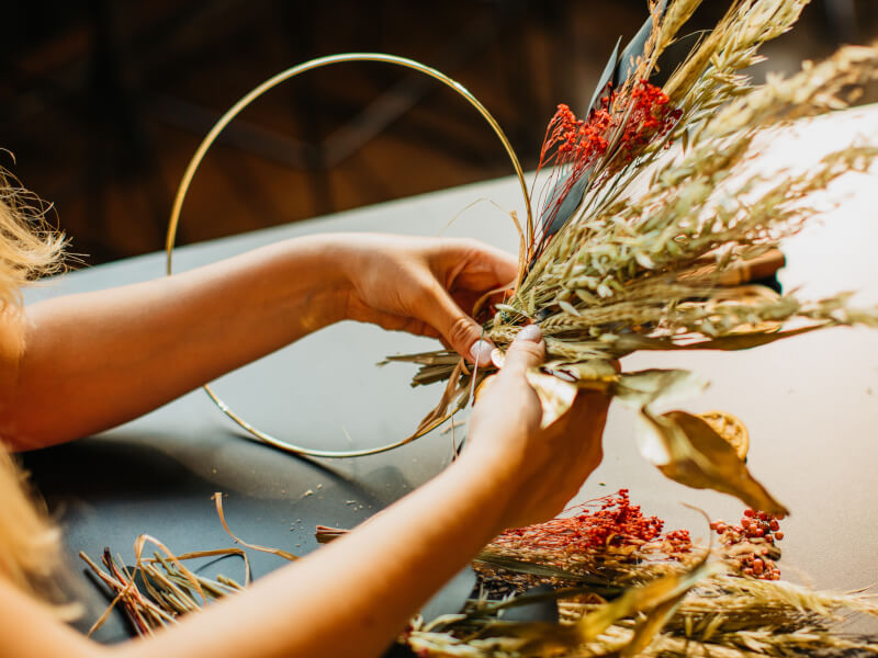 Hands making a dried flower wreath with metal hoop